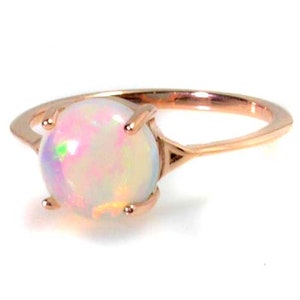 May include: A delicate rose gold ring with a round, iridescent opal gemstone.