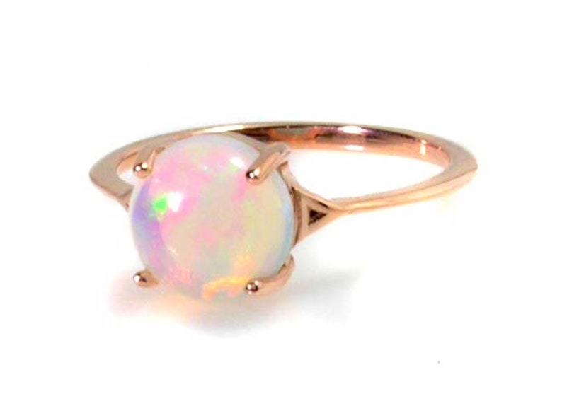 May include: A delicate rose gold ring with a round, iridescent opal gemstone.