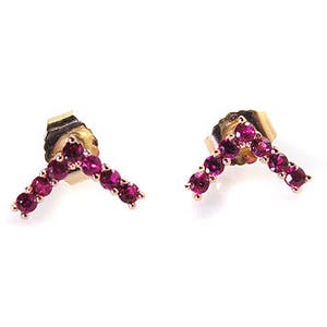 May include: A pair of gold earrings with a V-shaped design set with small, bright pink gemstones.