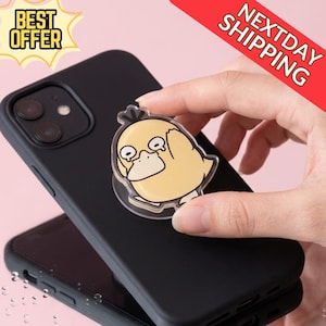 May include: A yellow cartoon duck phone grip is attached to a black phone case. The phone grip has a clear plastic backing. The words "BEST OFFER" are in a yellow banner in the upper left corner. The words "NEXTDAY SHIPPING" are in a red banner in the upper right corner.