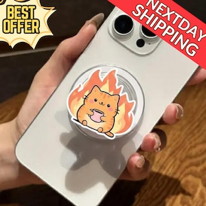 May include: A white mobile phone with a pop-up grip. The grip features an orange cartoon cat holding a pink cup, with flames behind it. The phone has a "Best Offer" and "Next Day Shipping" banner.