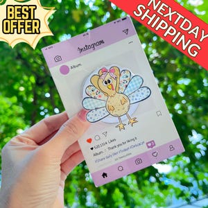 May include: A decorative turkey-themed phone grip with a pink bow, set against a mock Instagram post background. The grip features a cartoon turkey with floral and plaid wing details. The background includes Instagram icons and text.