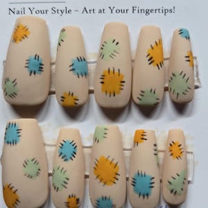 May include: Set of ten coffin-shaped false nails. Each nail is a light beige color and features a colorful patch design in yellow, blue, and green. The text "Nail Art" and "Nail Your Style - Art at Your Fingertips!" are visible.