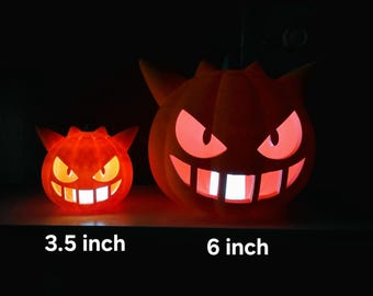 May include: Two orange, glowing, pumpkin-shaped Gengar figures with pointed ears and wide, toothy grins. The smaller figure is labeled 3.5 inch, and the larger figure is labeled 6 inch. Both items emit a bright light from their eyes and mouths.