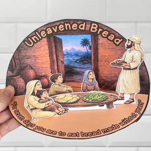 Puede incluir: Un recorte de papel que representa una escena bíblica con el texto "Pan sin levadura". La imagen muestra a una familia reunida alrededor de una mesa con comida, y un hombre sosteniendo una bandeja de pan. También está presente el texto "Durante siete días comeréis pan sin levadura".