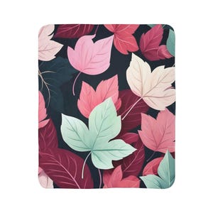 May include: A rectangular blanket with a repeating pattern of stylised leaves in shades of pink, red, and green against a dark background. The blanket has a soft appearance.