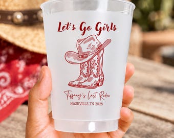 May include: A clear plastic cup featuring red printed text and graphics. The design includes a cowboy hat resting on a pair of cowboy boots, with the text Let's Go Girls, Tiffany's Last Rodeo, and NASHVILLE.TN 2026 printed in a red script and serif font.