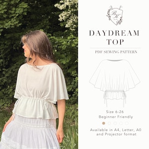 Può includere: Un top bianco a maniche corte con vita arricciata tramite coulisse e maniche svasate. L'immagine include un disegno tecnico del capo etichettato Daydream Top PDF Sewing Pattern, con taglie 6-26 e dettagli sui formati disponibili.