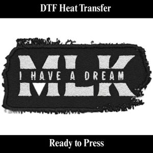 May include: Black rectangular heat transfer patch with white text that reads "MLK I HAVE A DREAM MLK". The patch has a distressed edge and is ready to press. The words "DTF Heat Transfer" and "Ready to Press" are also visible.