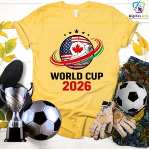 Może przedstawiać: Ż&oacute;łta koszulka z motywem piłki nożnej z flagami USA, Kanady i Meksyku, z napisem "WORLD CUP 2026". Zawiera piłki nożne, rękawice i trofeum.