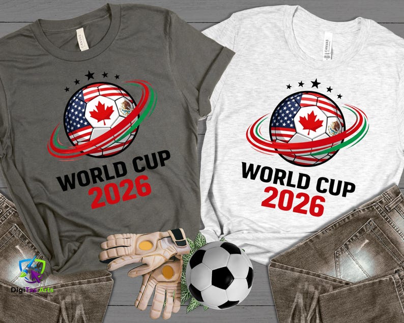 Może przedstawiać: Dwie koszulki, jedna szara i jedna biała, z motywem piłki nożnej z flagami USA, Kanady i Meksyku. Tekst "WORLD CUP 2026" jest wydrukowany poniżej w kolorze czarnym i czerwonym.