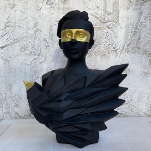 Könnte beinhalten: Schwarze Büstenskulptur mit einer Figur mit goldenen Akzenten über den Augen und einem goldenen Schnabel auf einem geometrischen Vogeldesign. Die Skulptur hat eine moderne, künstlerische Ästhetik und eignet sich für die Inneneinrichtung.