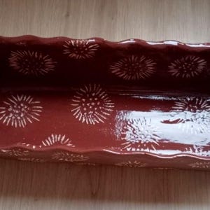 Pode incluir: Uma assadeira retangular de cerâmica marrom com borda ondulada. Decorada com padrões florais brancos estilizados. O interior é brilhante, o exterior fosco. Um artigo de cozinha decorativo para assar.