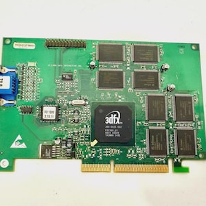 Puede incluir: Una placa de circuito verde con varios componentes electrónicos, incluyendo chips, conectores y un puerto VGA azul. La placa presenta el logotipo "3dfx" y otros textos, indicando su función como tarjeta gráfica. Diseñada para hardware informático.