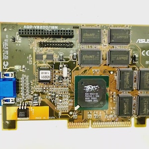 May include: A computer graphics card with a green circuit board. It features multiple chips, including those labeled "EliteMT" and a central processor with "3Dfx" branding. The card has a blue VGA connector and the text "ASUS".