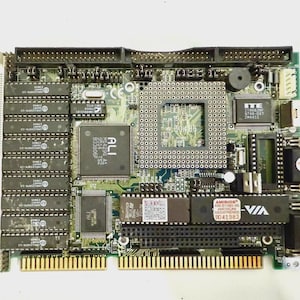 Pode incluir: Uma placa-mãe de computador verde e preta com vários circuitos integrados, slots e conectores. A placa possui chips rotulados como "ALI", "ITE" e "AMI BIOS". Possui vários slots para RAM e outras placas de expansão e um logotipo VIA.