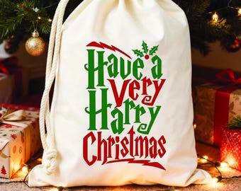 Może przedstawiać: Kremowy worek na prezent ze sznurkiem z napisem "Have a Very Harry Christmas" w kolorze zielonym i czerwonym. Torba znajduje się pod choinką z ozdobami i prezentami.