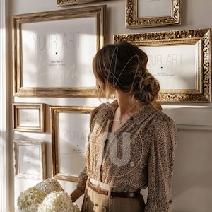 Puede incluir: Una colección de obras de arte enmarcadas en varios tamaños y estilos, con marcos dorados y de madera. Los marcos están montados en una pared blanca, con el texto "YOUR ART" visible en la obra de arte. Una persona está de pie frente a los marcos.