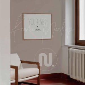 Puede incluir: Una maqueta de obra de arte enmarcada con el texto "YOUR ART" en un entorno de habitación. El marco es de color marrón claro y la obra de arte se muestra en una pared marrón claro. Una silla blanca con brazos de madera está en primer plano.