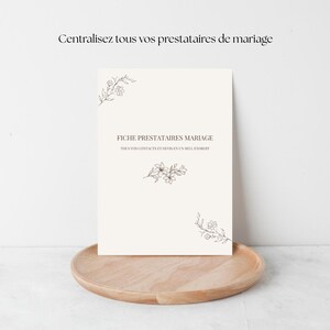 Peut inclure: Un document crème avec le texte "FICHE PRESTATAIRES MARIAGE" et des illustrations florales. Le document est posé sur un plateau en bois. Le texte "Centralisez tous vos prestataires de mariage" est en haut.