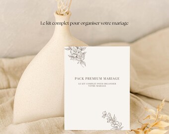 May include: A beige card with the text "PACK PREMIUM MARIAGE" and floral illustrations. The card is next to a beige vase with a dried flower arrangement. The text "Le kit complet pour organiser votre mariage" is above the card.