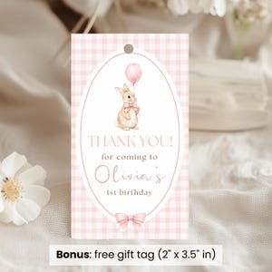 Op de afbeelding: Roze gingham cadeaulabel met een ovaal ontwerp met een aquarel illustratie van een konijn met een ballon. Tekst luidt: "THANK YOU! for coming to Olivia's 1st birthday." Inclusief een strik. Label afmetingen: 5,08 cm x 8,89 cm.