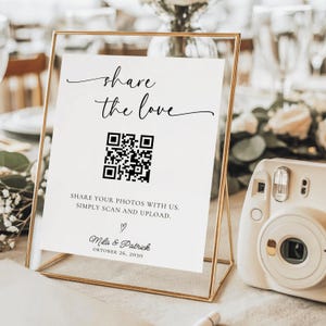 Könnte beinhalten: Ein goldgerahmtes Schild mit dem Schriftzug "share the love" in eleganter Schrift. Darunter befindet sich ein QR-Code und der Text "SHARE YOUR PHOTOS WITH US. SIMPLY SCAN AND UPLOAD." Das Schild enthält auch die Namen "Mila & Patrick" und das Datum "OKTOBER 26, 2030".