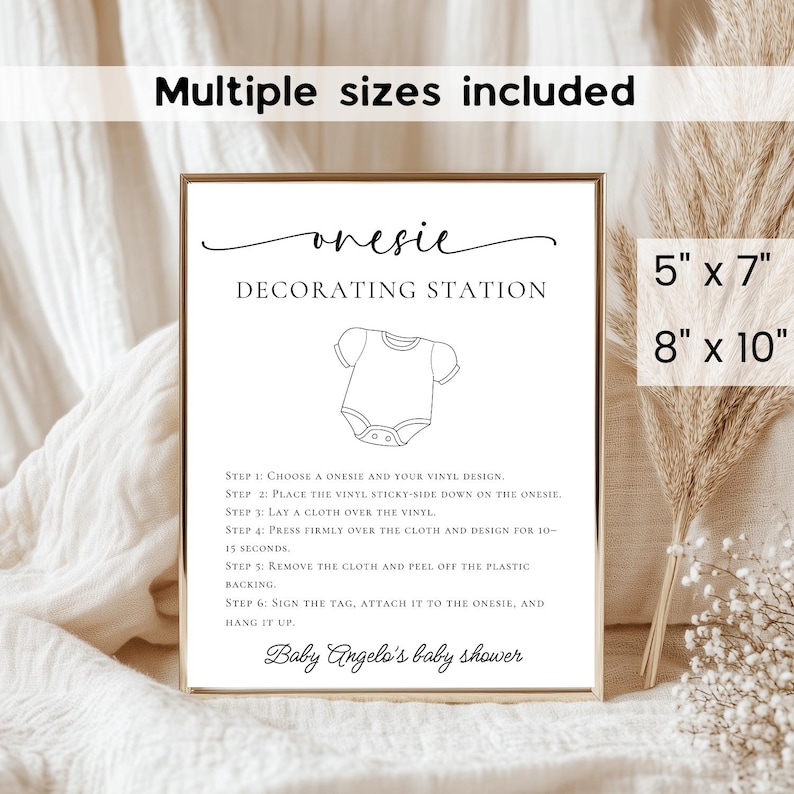 May include: A framed print with the text "onesie DECORATING STATION" and instructions for decorating baby onesies. The print includes the text "Baby Angelo's baby shower" and is available in 5" x 7" and 8" x 10" sizes.