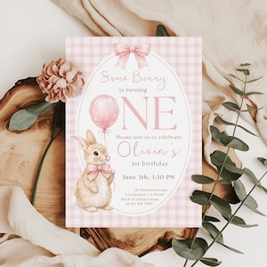 Op de afbeelding: Een roze en wit geruit uitnodigingskaart met de tekst "Some Bunny is turning ONE". De kaart toont een aquarel illustratie van een konijn met een ballon en een roze strik. De uitnodiging is voor Olivia's 1e verjaardag.