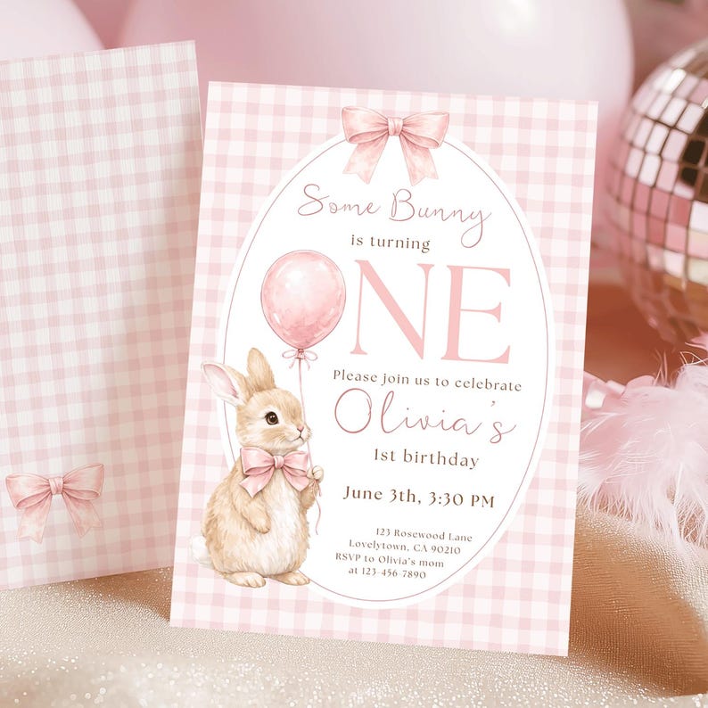 Op de afbeelding: Roze geruite uitnodiging met een illustratie van een konijn met een ballon. De tekst luidt "Some Bunny is turning ONE" en bevat feestdetails. Een bijpassende kaart met een strik staat links.
