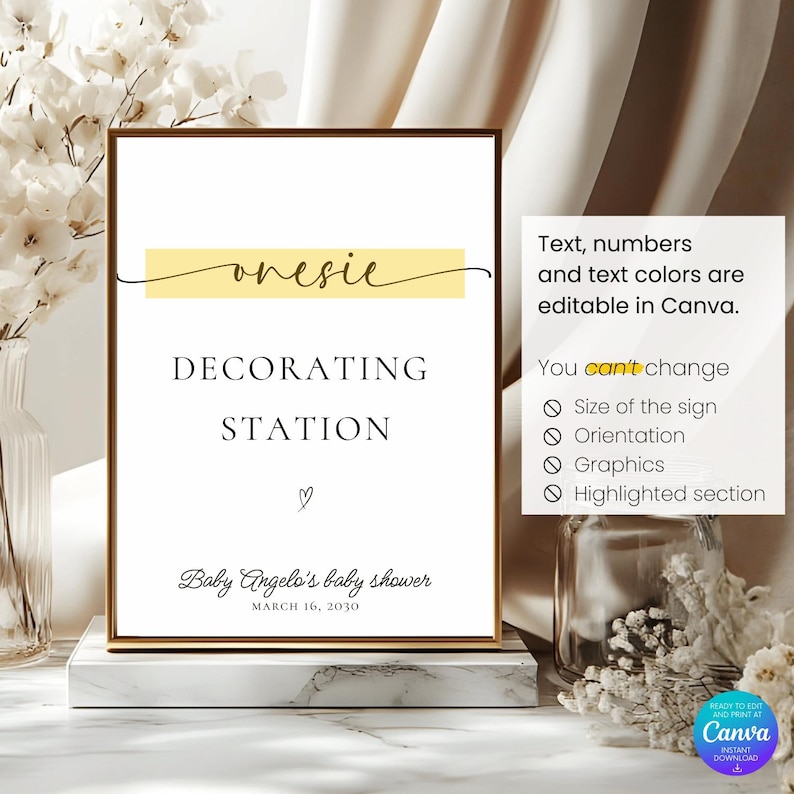 May include: A framed sign with the words "onesie DECORATING STATION" in black font, with a yellow banner above. Below, it reads "Baby Angelo's baby shower MARCH 16, 2030". The sign is on a marble base.