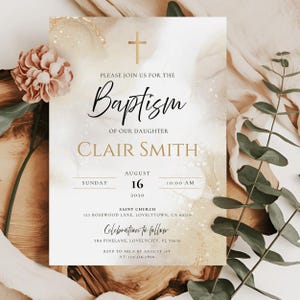 May include: Baptism invitation with gold cross and text. The invitation includes the name Clair Smith, date, time, and location. The design features a watercolor background with floral accents.