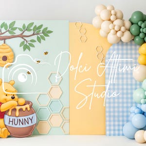Puede incluir: Un colorido telón de fondo con el tema de Winnie the Pooh. El diseño incluye un oso Pooh de dibujos animados con un tarro de miel, un panal y un arco de globos en colores pastel. El texto "Dolci Attimi Studio" también es visible.