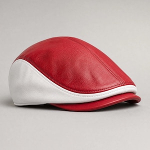 May include: A flat cap constructed from red and white leather panels. The main body features a vibrant red textured leather, while the side panels and a thin piping detail along the base are crafted from smooth white leather, with a red brim.