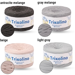 May include: Four spools of Trikolino yarn in various colors: anthracite melange, gray melange, beige, and light gray. Each spool has a label with the brand name and website address. The yarn is tightly wound, showing the texture of the material.