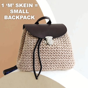 May include: A small, beige crocheted backpack with a dark brown leather flap and handle. The bag features a silver clasp closure and black drawstring straps. Text on the top reads "1 'M' SKEIN = SMALL BACKPACK".
