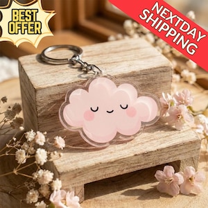 May include: A clear acrylic keyring with a pink cloud design and a smiling face. The keyring has a silver metal ring and chain. The words "BEST OFFER" are in a yellow starburst shape. The words "NEXTDAY SHIPPING" are in a red banner.