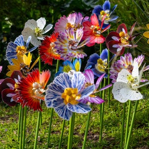May include: A collection of colorful paper flowers with intricate designs. The flowers are made of paper and have a variety of colors, including red, blue, white, yellow, and purple. The flowers are arranged in a cluster and are all facing the camera.