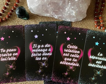 May include: A collection of black tarot cards with pink and purple accents, featuring text and butterfly illustrations. A large, light pink crystal and a beaded necklace are in the background.