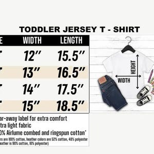 Op de afbeelding: Wit peuter jersey T-shirt met maattabel. De tabel toont maten 2T tot 5T, met breedtes van 30,5 cm tot 38,1 cm en lengtes van 39,4 cm tot 47 cm. Inclusief jeans, sneakers en kleurpotloden.