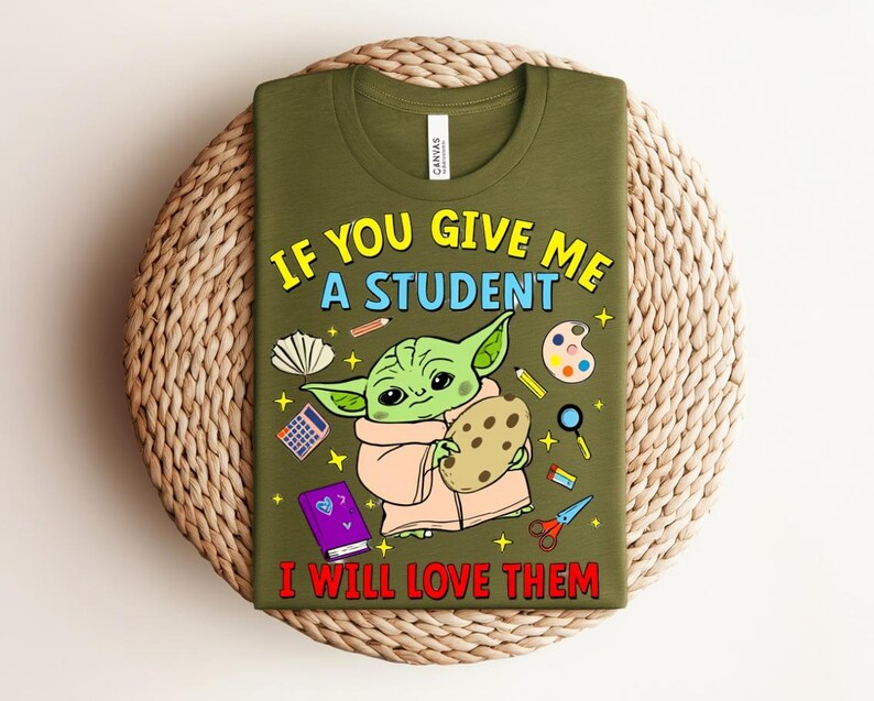 May include: Olive green t-shirt with a cartoon character holding a cookie, and school-themed illustrations. The text on the shirt reads, "IF YOU GIVE ME A STUDENT I WILL LOVE THEM."