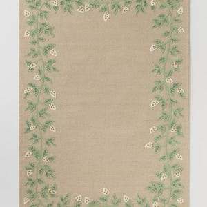 May include: Beige rectangular rug featuring an embroidered border of green leaves and white floral details. The design creates a frame around the central area of the rug, offering a decorative and natural look. Suitable for indoor use.