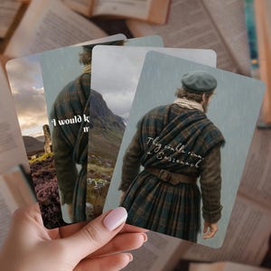 Może przedstawiać: Ręka trzyma karty z mężczyzną w tradycyjnym szkockim stroju. Karty przedstawiają obrazy mężczyzny w kilcie i frazy takie jak "I would know" i "Thig còmhla rium, a Sassenach". Otwarta książka w tle.