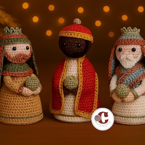 Peut inclure: Trois figurines au crochet faites à la main représentant les Rois Mages. Chaque figurine présente des détails uniques, avec des couleurs or, rouge et vert. Elles tiennent de petites sphères vertes. L'arrière-plan est flou avec des lumières chaudes et scintillantes.