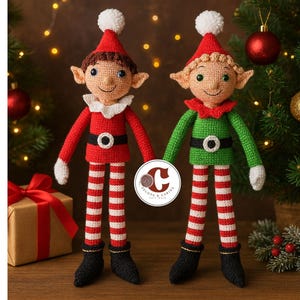 Peut inclure: Deux poupées elfes faites à la main au crochet. L'un porte une tenue rouge avec un col blanc, une ceinture noire et des jambes rayées. L'autre porte une tenue verte. Les deux ont des chapeaux rouges avec des pompons blancs et des chaussures noires. Décor de Noël en arrière-plan.