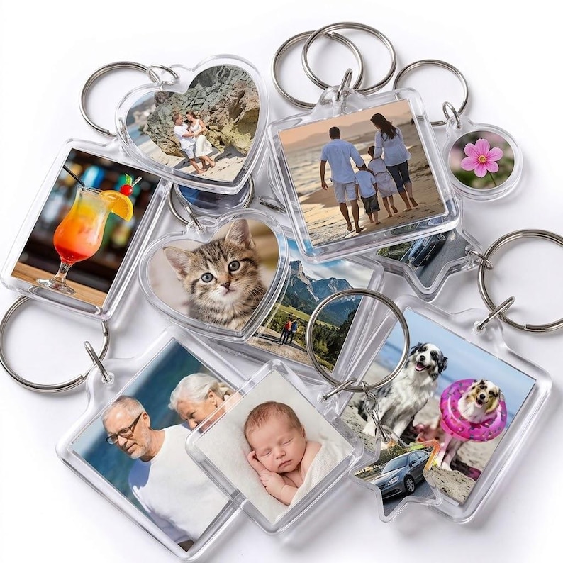 May include: A collection of clear acrylic keychains in various shapes, each featuring a different image. The keychains display photos of a family, a kitten, a cocktail, a flower, and other images. Each keychain has a silver metal ring.