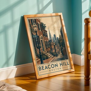 May include: A framed art print featuring a street scene of Beacon Hill in Boston. The illustration depicts brick buildings, a street lamp, and a sign reading ACORN ST. The text BEACON HILL BOSTON is printed in bold blue letters at the bottom.