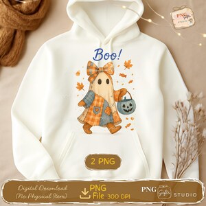 以下が含まれることがあります： ハロウィーンをテーマにしたグラフィックが施された白いパーカー。デザインは、リボン、パッチワークのドレス、カボチャのバケツを持つ幽霊のキャラクターが特徴です。「Boo！」という言葉が幽霊の上に書かれています。デジタルダウンロードが含まれています。