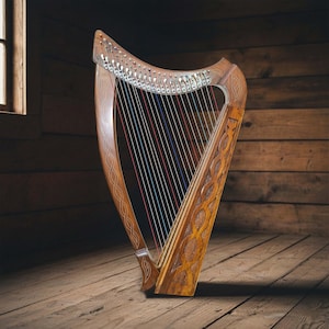 Op de afbeelding: Een gedetailleerde houten harp met gesneden patronen en veelkleurige snaren. De harp staat tegen een achtergrond van houten planken, wat een warme, rustieke sfeer creëert. Het ontwerp van het instrument heeft Keltische knoopwerk.