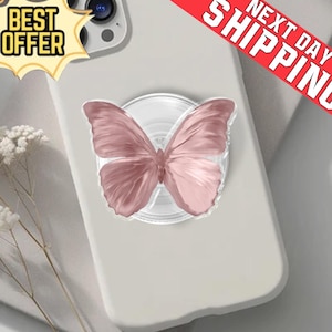 May include: A pale grey phone case with a pink butterfly phone grip. The butterfly has detailed wing patterns and a gradient of pink hues. The phone case has a "BEST OFFER" sticker in the upper left corner and a "NEXT DAY SHIPPING" banner.